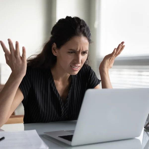 A woman sits at a desk with her hands outstretched, inquiring about a loan without refusal.
