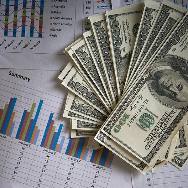 Stack of cash on financial reports illustrating the risk of requesting too much money in a loan